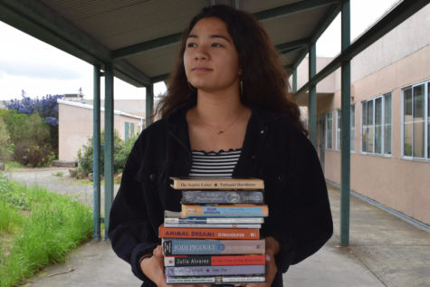 Reporter Taya Llapitan holds some staples of the schools literature curriculum.